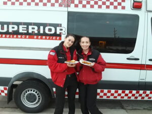 Val and her partner holding food in front of an ambulance