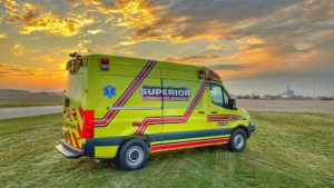 Full Yellow Superior-Branded Ambulance in field in front of sunset
