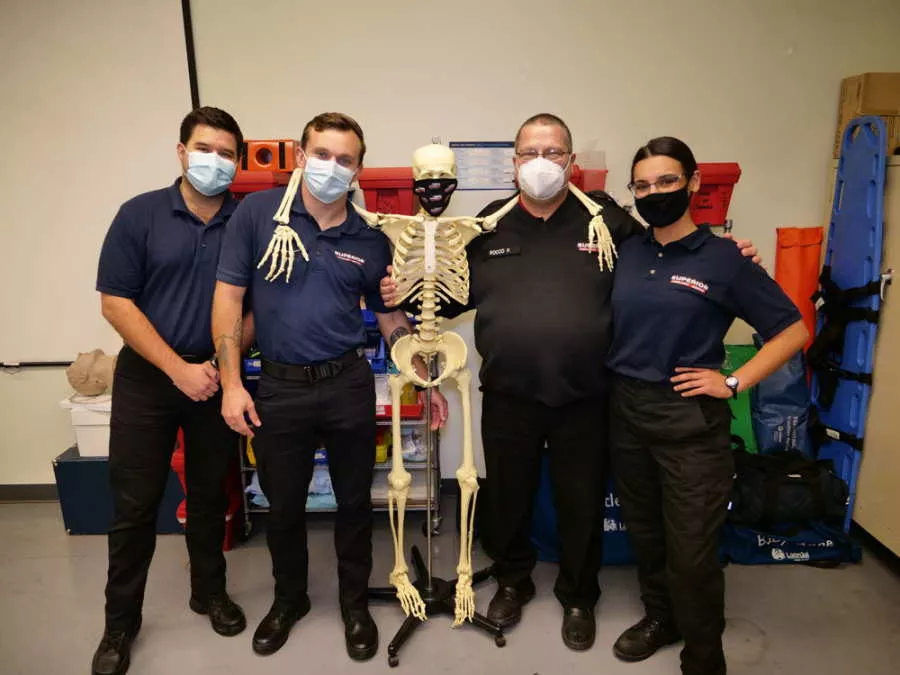 EMT Students Standing With Model Skeleton