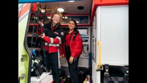 Two Superior Ambulance EMTs Smiling and Standing Inside of Ambulance
